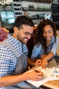 man and woman smiling at a table with a laptop